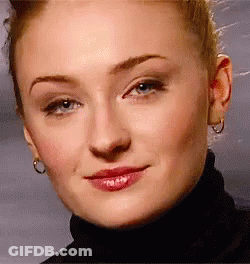 A Close Up Of A Woman 'S Face Wearing A Turtleneck And Earrings . GIF