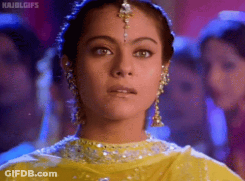 A Close Up Of A Woman 'S Face Wearing A Yellow Dress And Earrings GIF