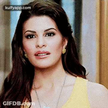 A Close Up Of A Woman 'S Face Wearing A Yellow Top And Earrings . GIF