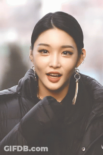 A Close Up Of A Woman 'S Face Wearing Earrings And A Black Jacket GIF