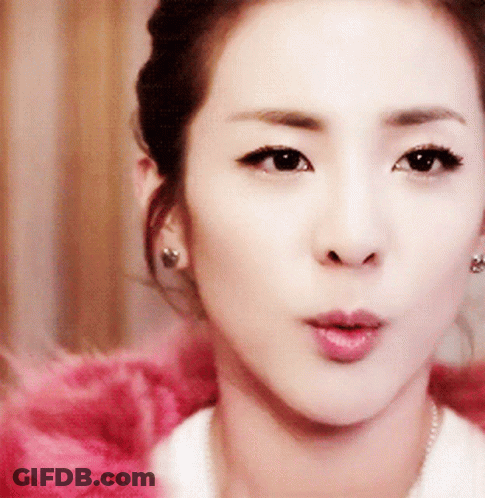 A Close Up Of A Woman 'S Face Wearing Earrings And A White Shirt GIF