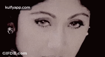 A Close Up Of A Woman 'S Face Wearing Earrings And Looking At The Camera . GIF