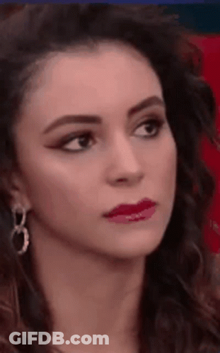 A Close Up Of A Woman 'S Face Wearing Earrings And Red Lipstick . GIF