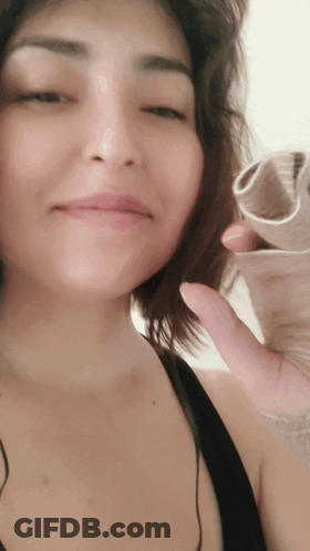 A Close Up Of A Woman 'S Face While Holding A Piece Of Paper GIF