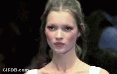 A Close Up Of A Woman 'S Face While Walking Down A Runway At A Fashion Show . GIF