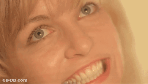 A Close Up Of A Woman 'S Face With A Big Smile GIF