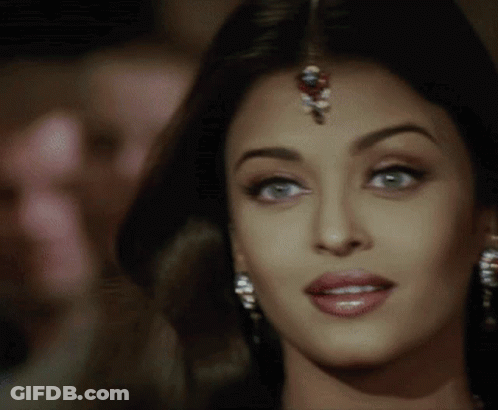 A Close Up Of A Woman 'S Face With A Bindi On Her Forehead And Earrings . GIF