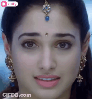 A Close Up Of A Woman 'S Face With A Bindi On Her Forehead And Earrings . GIF