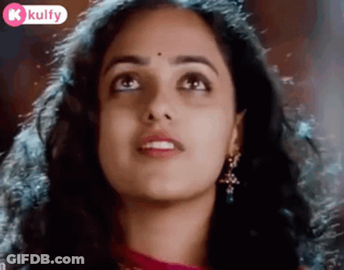 A Close Up Of A Woman 'S Face With A Bindi On Her Forehead Looking Up . GIF
