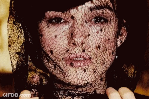 A Close Up Of A Woman 'S Face With A Black Lace Veil GIF