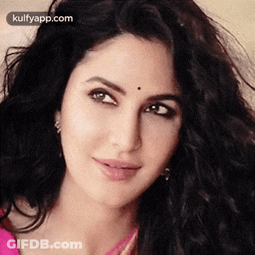 A Close Up Of A Woman 'S Face With A Black Spot On Her Forehead And A Pink Shirt . GIF