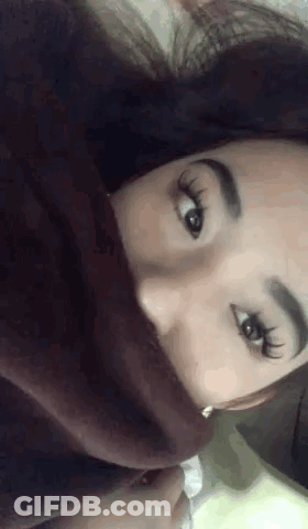A Close Up Of A Woman 'S Face With A Blanket Covering Her Mouth . GIF