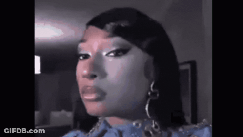 A Close Up Of A Woman 'S Face With A Blue Dress And Earrings . GIF