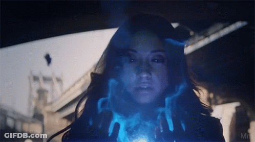 A Close Up Of A Woman 'S Face With A Blue Light Coming Out Of Her Hands GIF