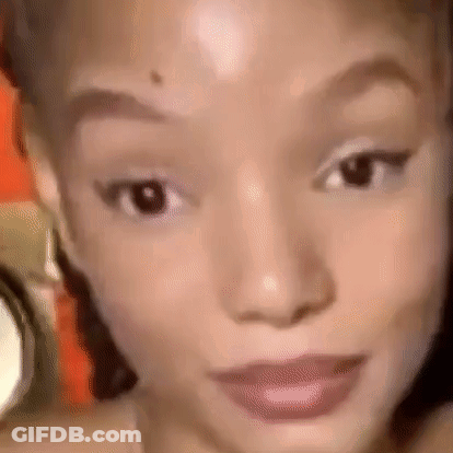 A Close Up Of A Woman 'S Face With A Blurred Background Looking At The Camera . GIF