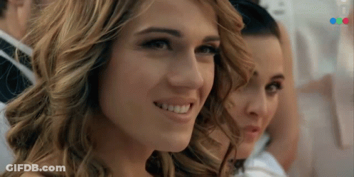 A Close Up Of A Woman 'S Face With A Blurred Image Of A Man In A Suit Behind Her GIF