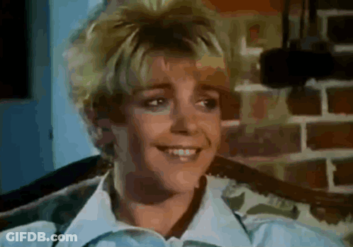 A Close Up Of A Woman 'S Face With A Brick Wall In The Background GIF