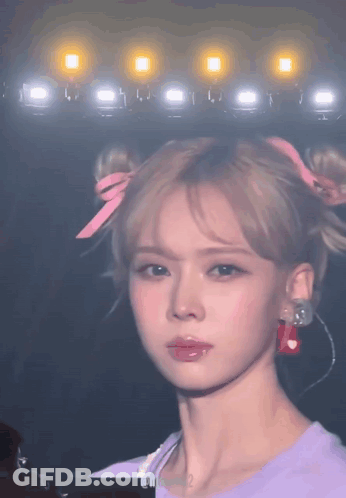 A Close Up Of A Woman 'S Face With A Bun And Earrings GIF