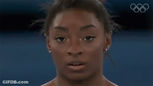 A Close Up Of A Woman 'S Face With A Bun In Her Hair And Earrings . GIF
