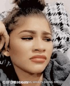 A Close Up Of A Woman 'S Face With A Bun On Her Head And A Sad Look On Her Face . GIF