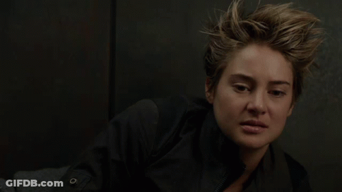 A Close Up Of A Woman 'S Face With A Button On Her Jacket GIF