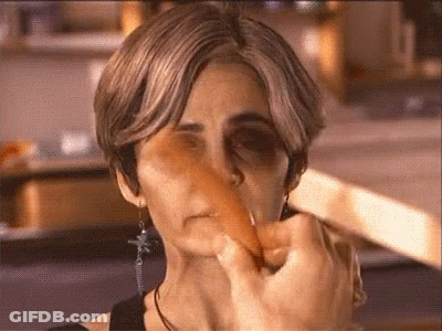 A Close Up Of A Woman 'S Face With A Carrot Sticking Out Of It GIF