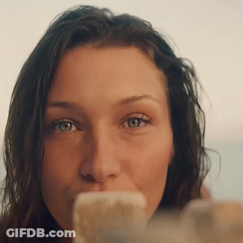A Close Up Of A Woman 'S Face With A Cell Phone In Her Mouth GIF
