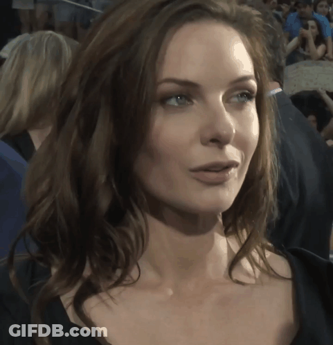 A Close Up Of A Woman 'S Face With A Crowd Of People Behind Her GIF