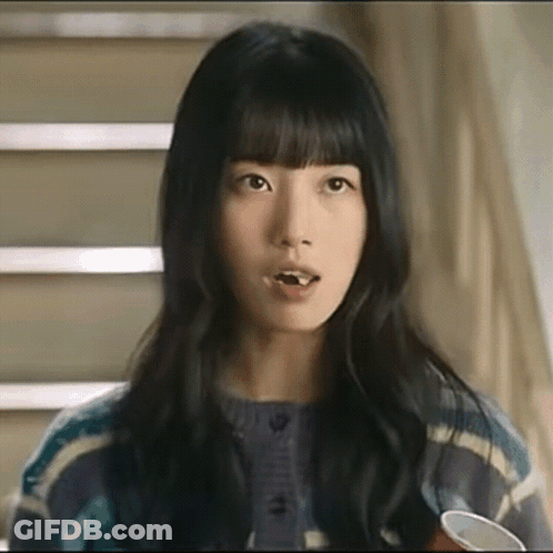 A Close Up Of A Woman 'S Face With A Cup In Her Hand And Stairs In The Background . GIF