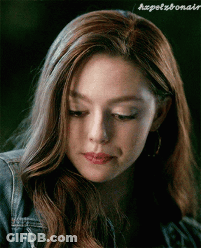 A Close Up Of A Woman 'S Face With A Denim Jacket And Earrings . GIF