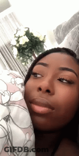 A Close Up Of A Woman 'S Face With A Floral Blanket In The Background GIF