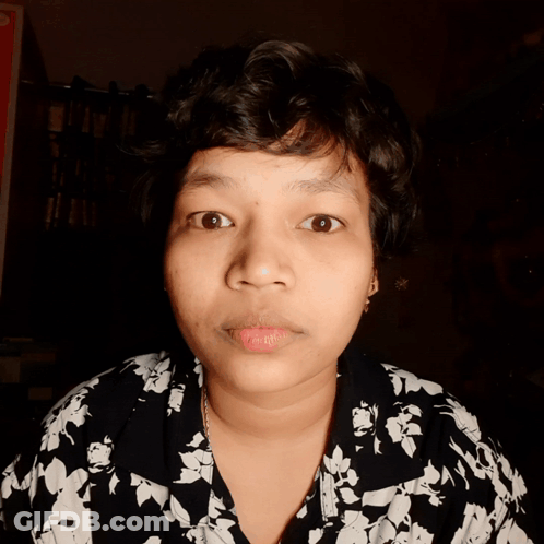 A Close Up Of A Woman 'S Face With A Floral Shirt GIF