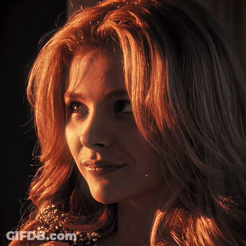 A Close Up Of A Woman 'S Face With A Flower In Her Hair GIF