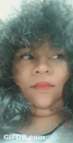A Close Up Of A Woman 'S Face With A Furry Hat And Red Lipstick . GIF
