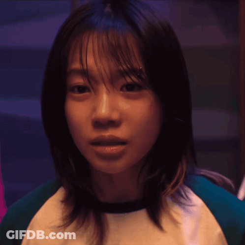 A Close Up Of A Woman 'S Face With A Green And White Shirt On GIF