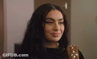 A Close Up Of A Woman 'S Face With A Guitar Strap Around Her Shoulder . GIF