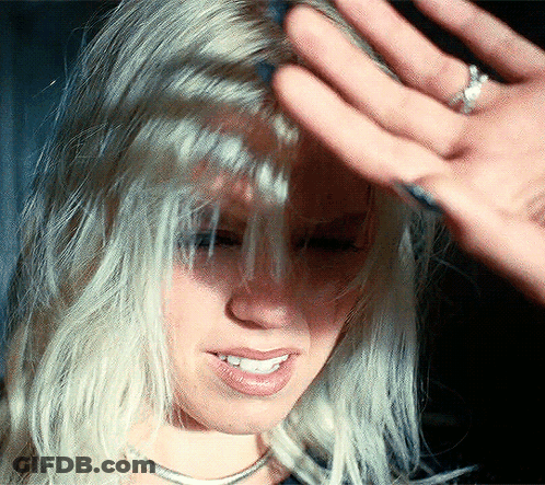 A Close Up Of A Woman 'S Face With A Hand On Her Forehead GIF