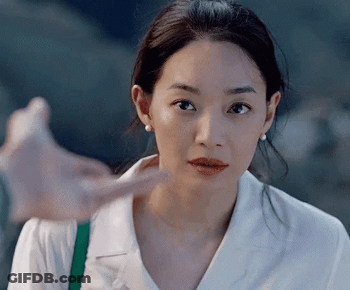 A Close Up Of A Woman 'S Face With A Hand Pointing To Her Face . GIF