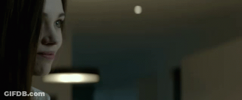 A Close Up Of A Woman 'S Face With A Light In The Background GIF