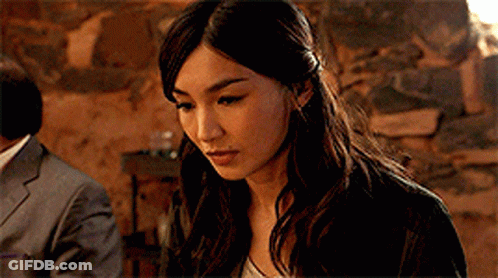 A Close Up Of A Woman 'S Face With A Man In A Suit In The Background GIF