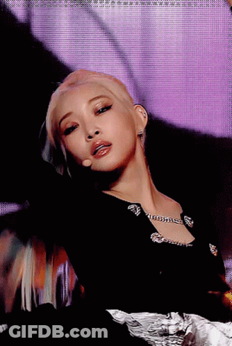 A Close Up Of A Woman 'S Face With A Microphone In Front Of Her GIF