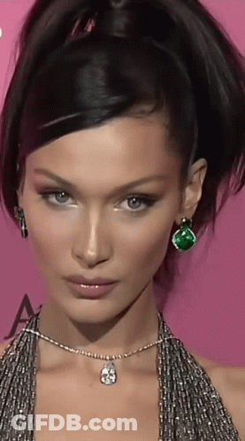A Close Up Of A Woman 'S Face With A Necklace And Earrings GIF