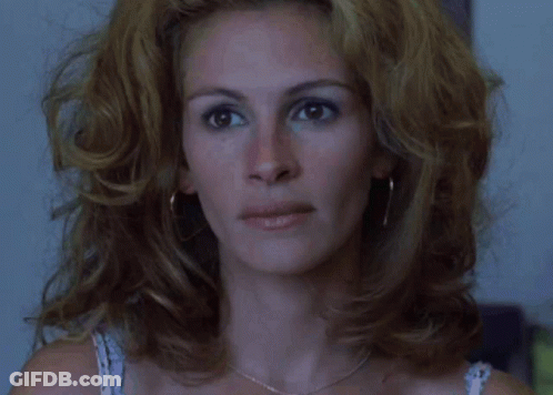 A Close Up Of A Woman 'S Face With A Necklace And Earrings GIF