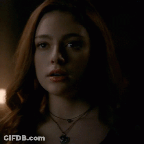 A Close Up Of A Woman 'S Face With A Necklace Around Her Neck . GIF