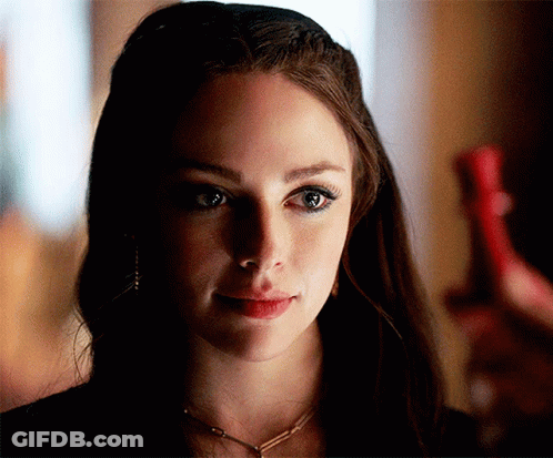 A Close Up Of A Woman 'S Face With A Necklace Around Her Neck GIF