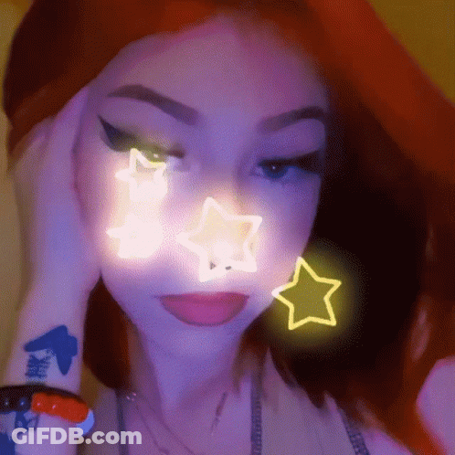 A Close Up Of A Woman 'S Face With A Neon Star On It . GIF