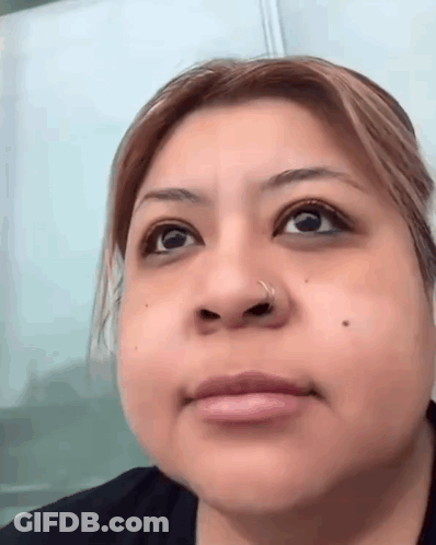 A Close Up Of A Woman 'S Face With A Nose Ring And A Black Shirt . GIF