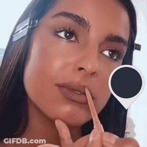 A Close Up Of A Woman 'S Face With A Pencil In Her Mouth GIF