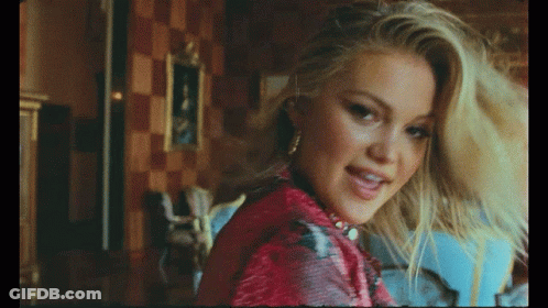 A Close Up Of A Woman 'S Face With A Picture In The Background GIF