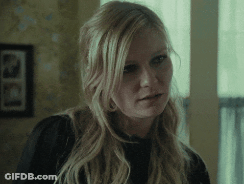 A Close Up Of A Woman 'S Face With A Picture Of A Man On The Wall Behind Her GIF